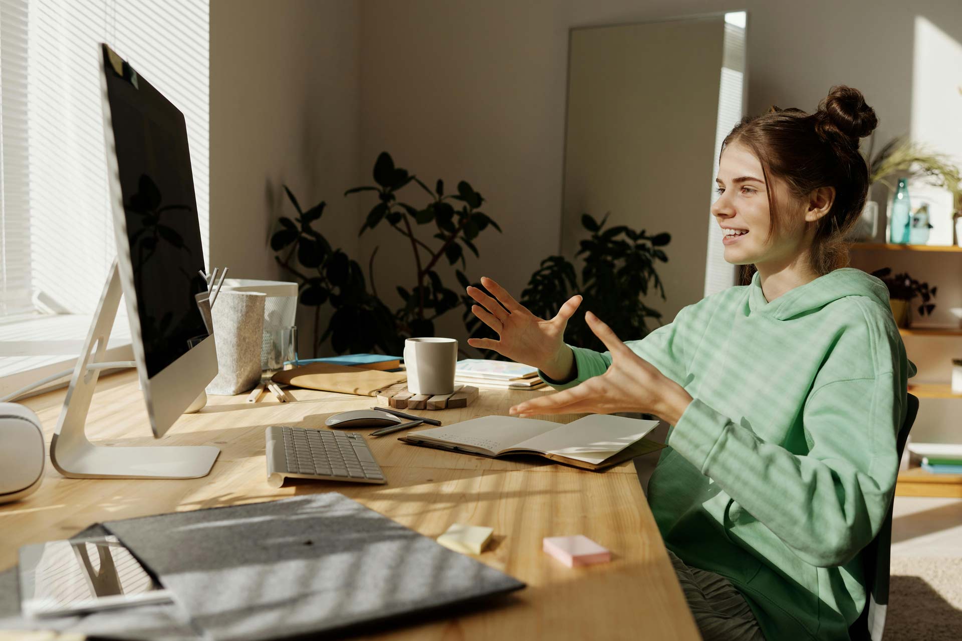 Eine lächelnde Frau, die einen Laptop benutzt und im Meeting etwas erklärt.